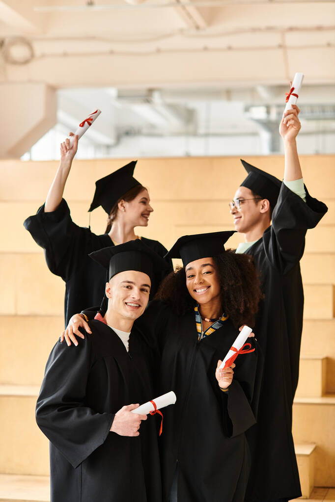 Diverso gruppo di studenti in abiti di laurea e tappi in posa felicemente per una foto. - Foto, immagini
