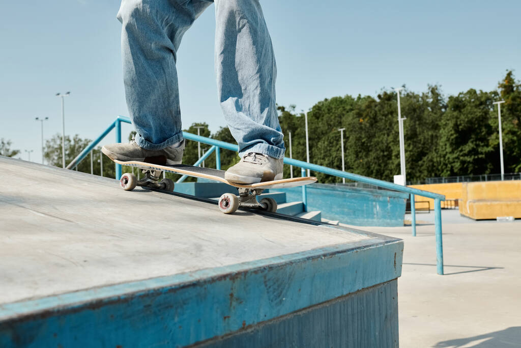 Um jovem patinador cavalga destemidamente seu skate para baixo do lado de uma rampa em um parque de skate em um dia ensolarado de verão. - Foto, Imagem