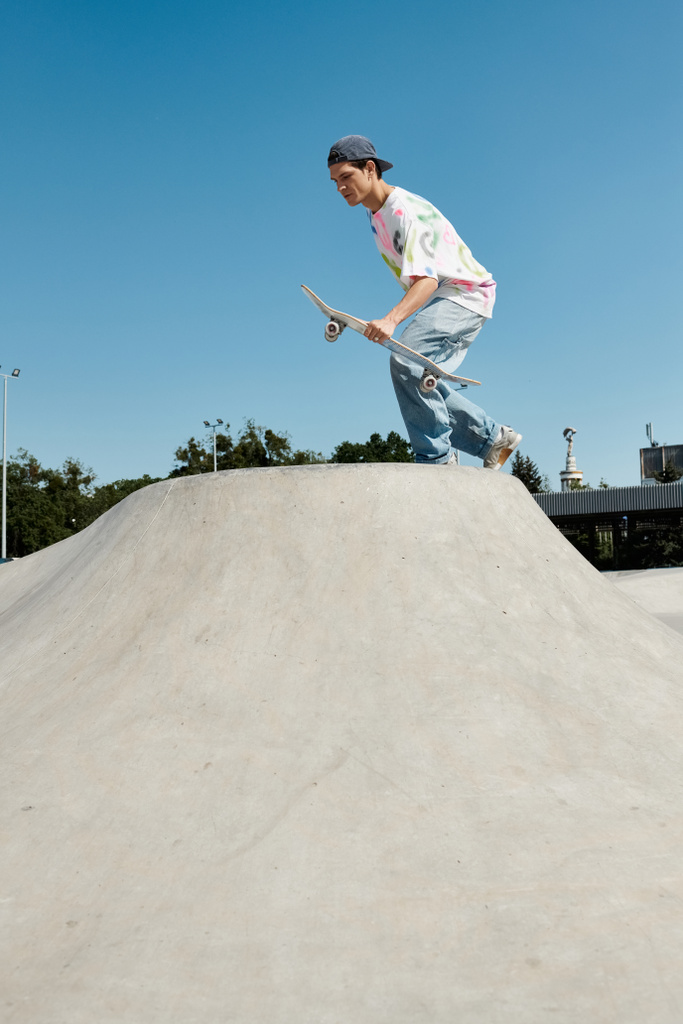 Un ragazzo skater cavalca con fiducia il suo skateboard lungo il lato ripido di una rampa in un parco di pattini all'aperto in una giornata estiva soleggiata. - Foto, immagini
