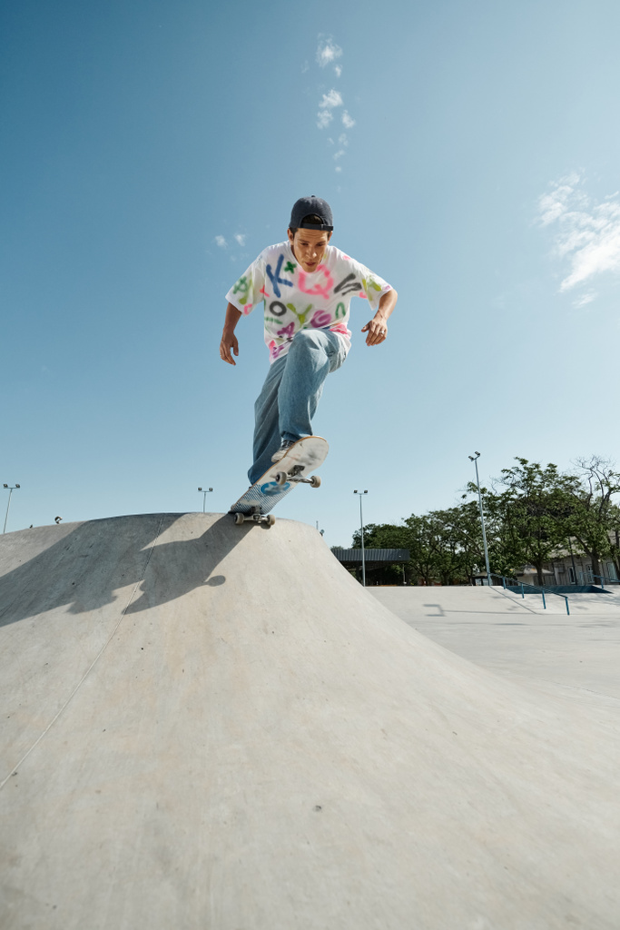 Young skater boy rides skateboard down side of outdoor ramp in summer skate park. - Photo, Image