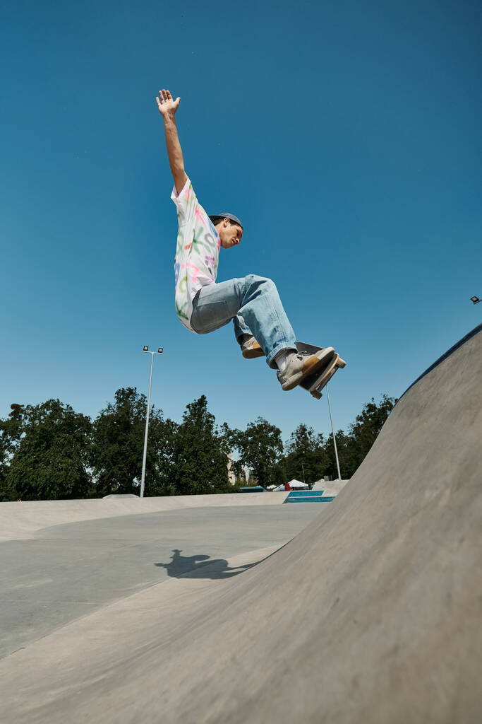 Ein junger Skater-Junge fährt an einem sonnigen Sommertag furchtlos mit einem Skateboard die Seite einer Rampe in einem belebten Outdoor-Skatepark hinauf. - Foto, Bild