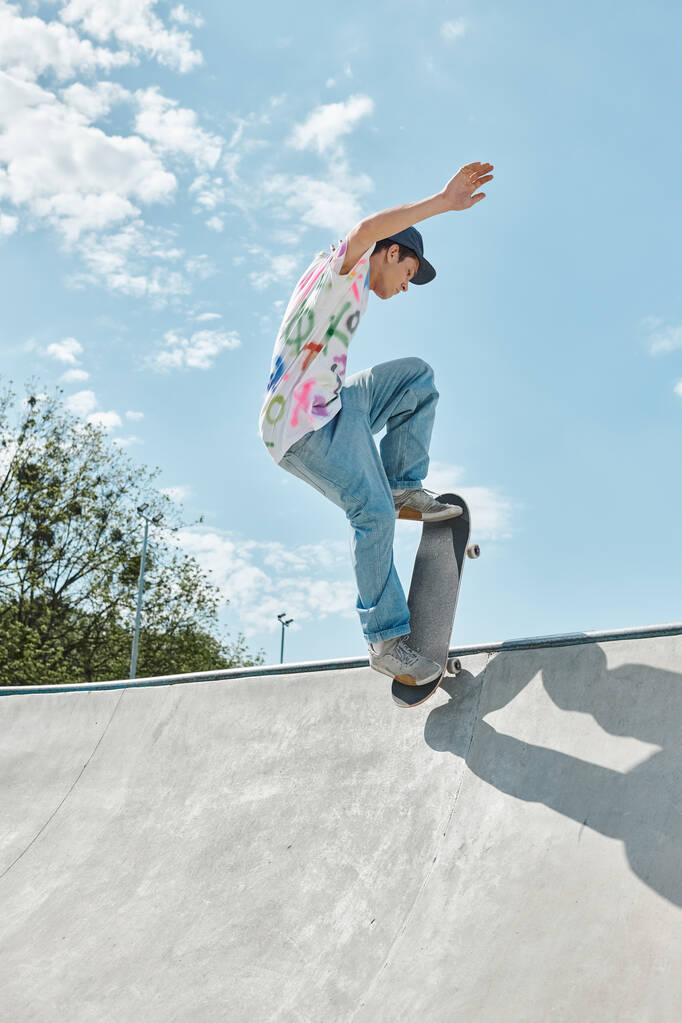 Молодой скейтбордист бесстрашно скачет на скейтборде по склону пандуса в открытом скейтпарке в солнечный летний день.. - Фото, изображение
