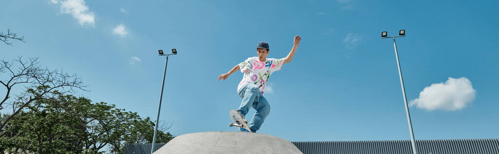Um jovem patinador atrevidamente monta seu skate em cima de uma rampa de cimento em um parque de skate ao ar livre em um dia de verão. - Foto, Imagem