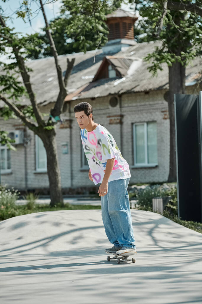 Ένα νεαρό αγόρι σκέιτερ γρήγορα οδηγεί ένα skateboard κάτω από ένα πεζοδρόμιο της πόλης σε μια ηλιόλουστη μέρα του καλοκαιριού, δείχνοντας τις ικανότητές του και το πάθος του για το άθλημα. - Φωτογραφία, εικόνα