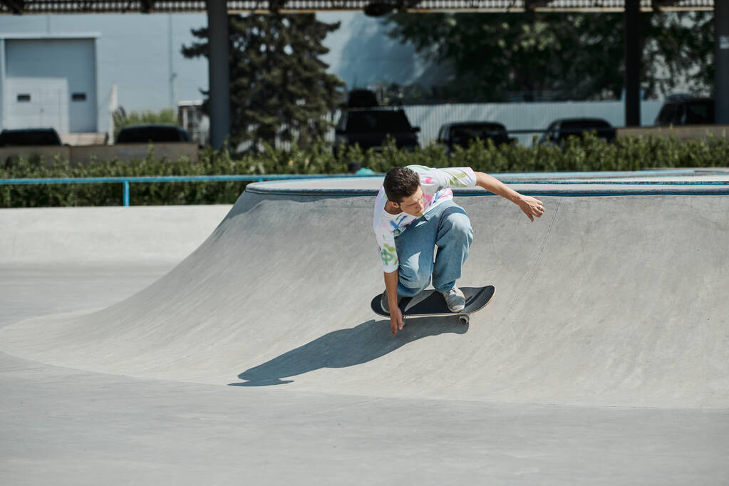 Um jovem patinador montando um skate até uma rampa íngreme em um parque de skate ao ar livre em um dia ensolarado de verão. - Foto, Imagem