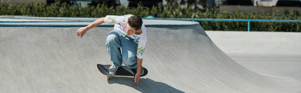 Een jonge skater jongen rijdt op een skateboard langs een helling bij een skate park op een zomerdag. - Foto, afbeelding
