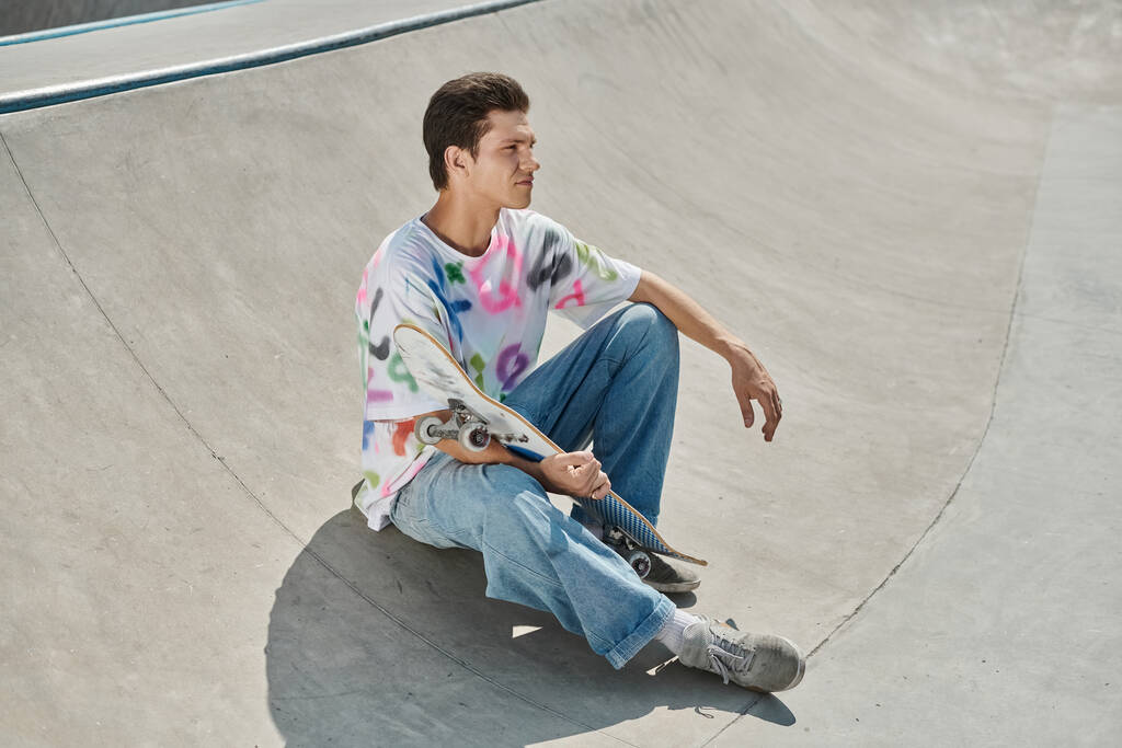 Молодий ковзаняр демонструє свої навички, сидячи на скейтборді в яскравому скейт-парку. - Фото, зображення