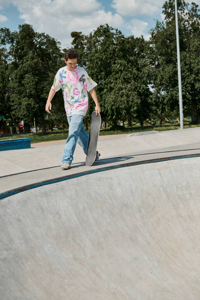 Un giovane skater boy che cammina con lo skateboard su una ripida rampa in uno skate park in una giornata estiva soleggiata. - Foto, immagini