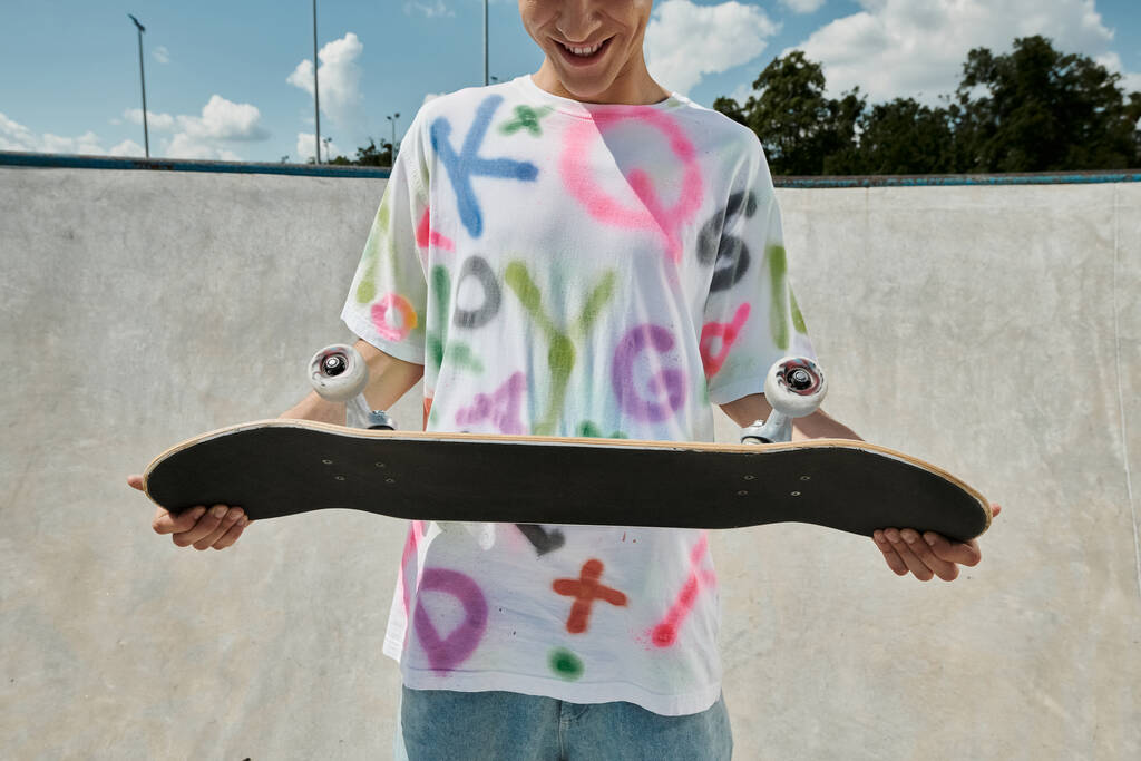 Un giovane uomo con uno skateboard in un vivace skate park, catturando l'essenza della libertà e dell'adrenalina mentre pattina all'aperto in estate. - Foto, immagini