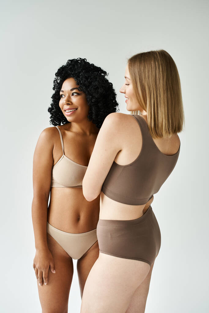 Kaksi monipuolista naista kodikas pastelli alusvaatteet seistä rinnakkain. - Valokuva, kuva