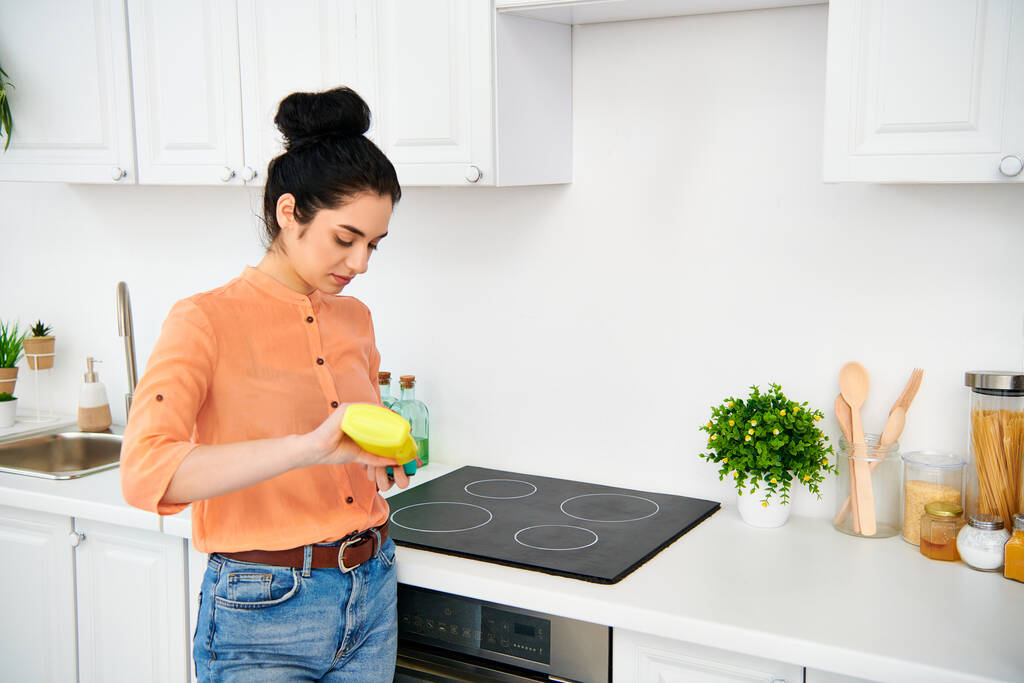 Een stijlvolle vrouw in casual kleding staat in een keuken, met een felgele frisbee. - Foto, afbeelding