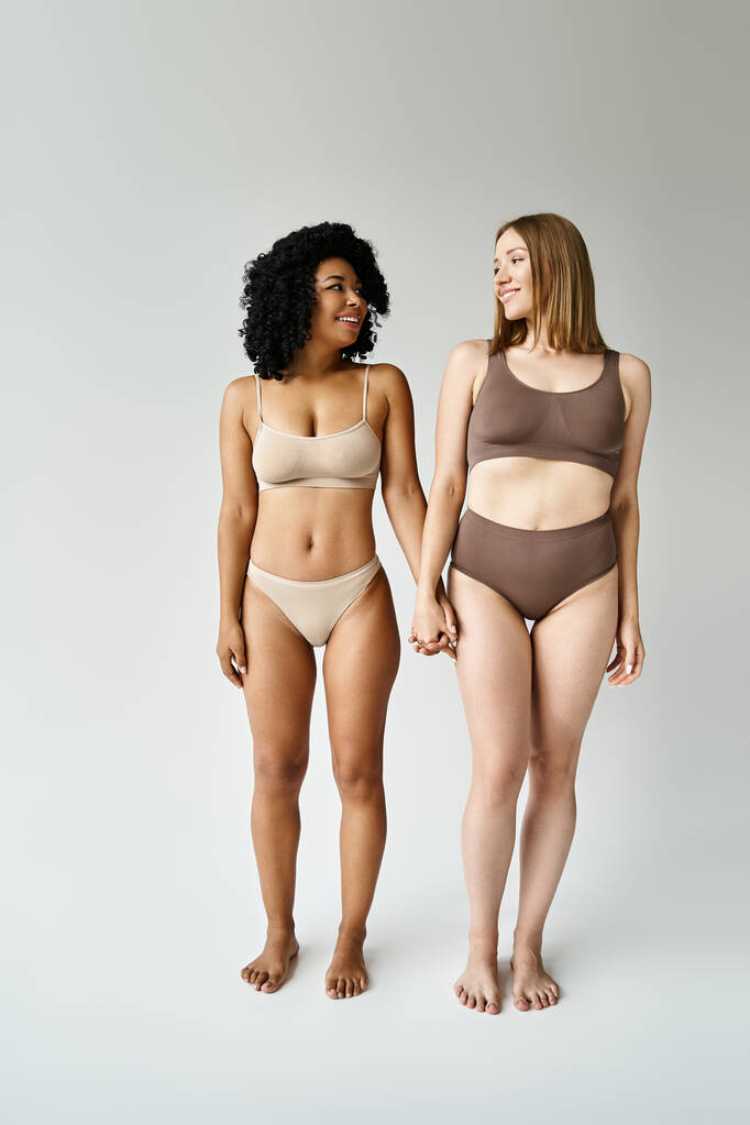Due donne diverse in accoglienti bikini pastello in piedi insieme. - Foto, immagini