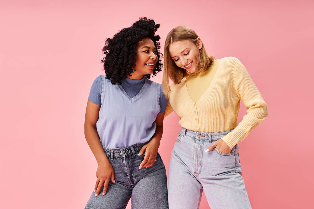Zwei unterschiedliche Frauen stehen stilvoll vor pinkfarbener Kulisse. - Foto, Bild