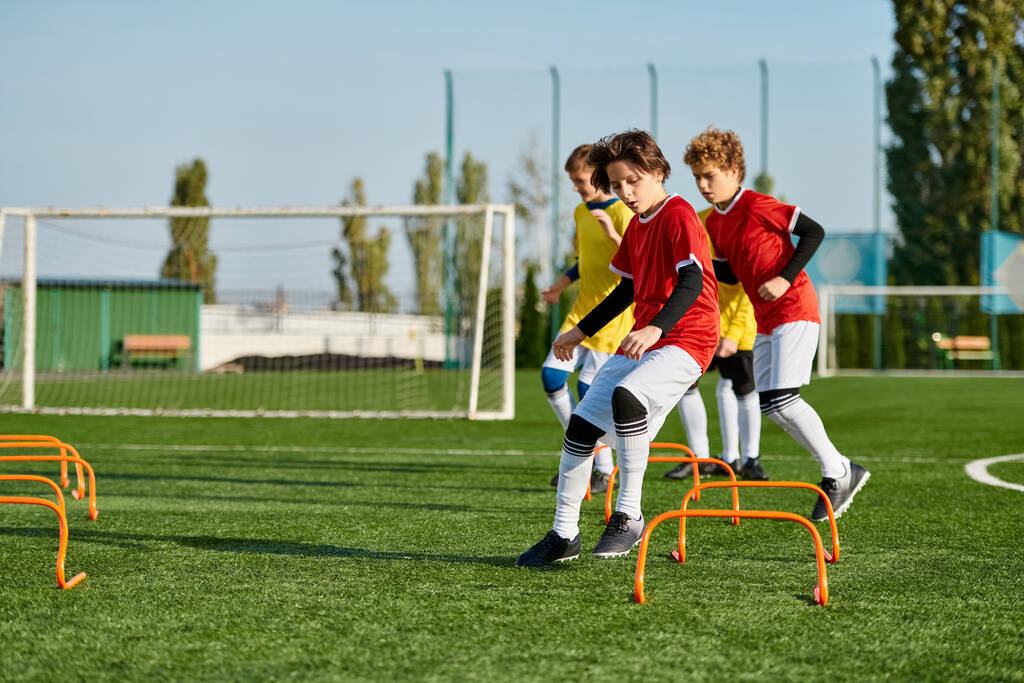 Skupina energických mladých chlapců, kteří hrají fotbal na travnatém poli, kopají do míče, běhají a smějí se, když spolu soupeří v přátelském zápase. - Fotografie, Obrázek