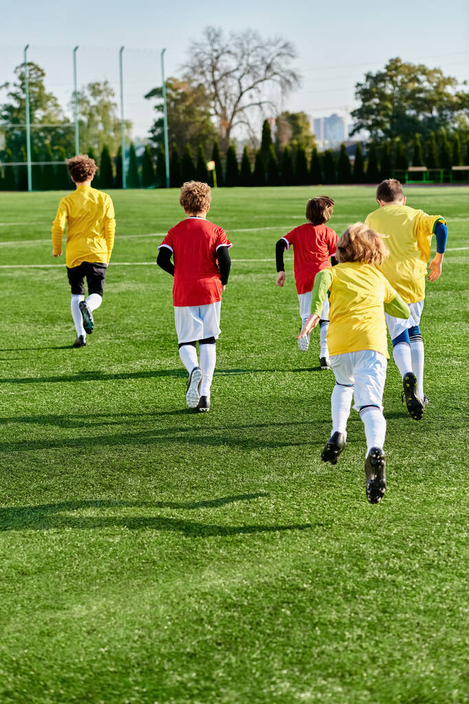 Pełna życia grupa małych dzieci entuzjastycznie grająca w piłkę nożną na zielonym polu, kopiąca piłkę, biegająca, dopingująca i prezentująca pracę zespołową i sportową. - Zdjęcie, obraz