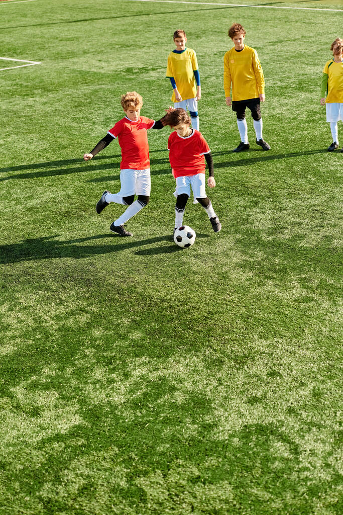 Un groupe de jeunes enfants jouant énergiquement à un jeu de football sur un terrain herbeux. Ils courent, dribblent, passent et donnent des coups de pied au ballon avec enthousiasme et travail d'équipe. - Photo, image