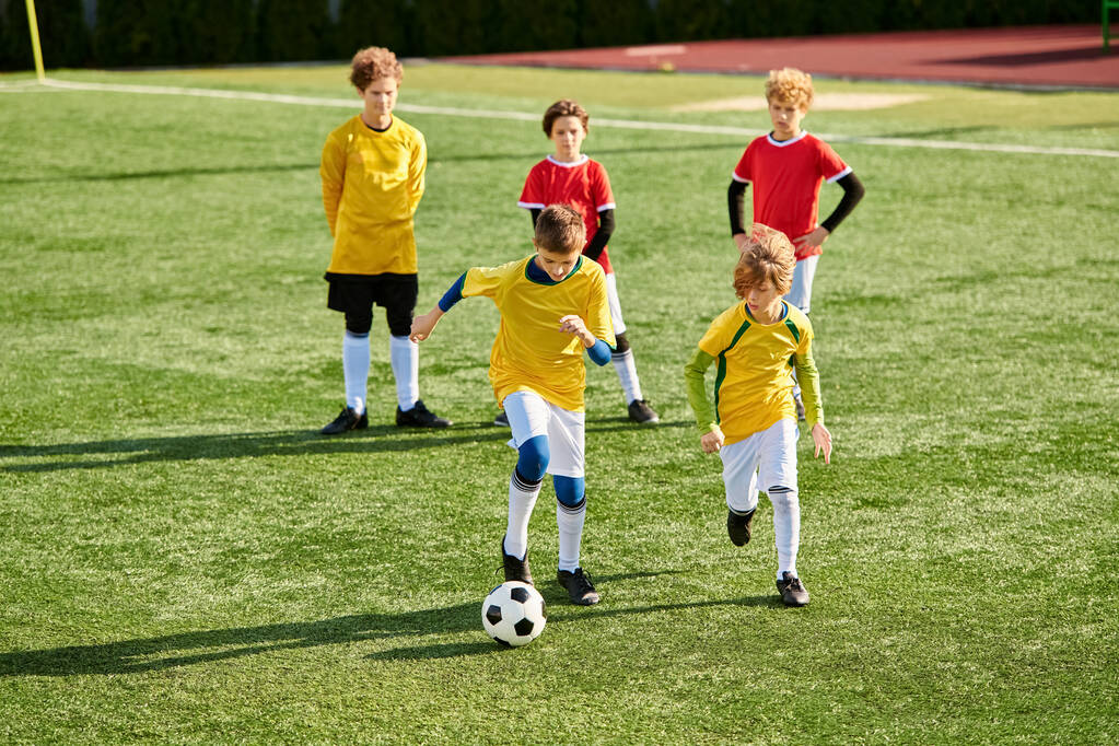 Группа мальчиков играет в интенсивную игру в футбол на травянистом поле. Они бегут, пинают мяч и болеют друг за друга, соревнуясь в товарищеском, но соревновательном матче.. - Фото, изображение