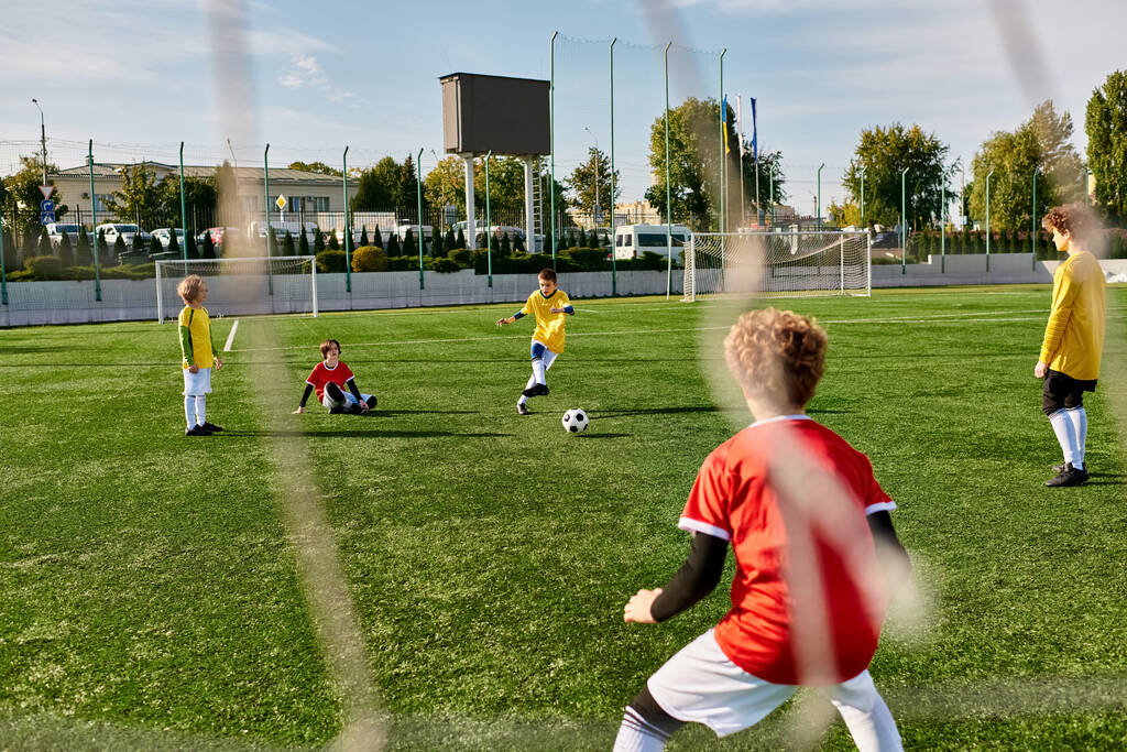 Skupina malých dětí hraje energickou fotbalovou hru na travnatém poli. Běží, míjí a kopají do míče s nadšením a týmovou prací. Děti se smějí a jásají, když se zapojují do přátelské soutěže. - Fotografie, Obrázek