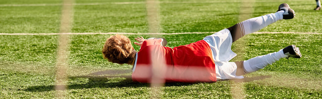 Une personne en tenue décontractée couchée sur le sol, l'air détendue, à côté d'un ballon de football. Le soleil brille, projetant des ombres sur le sol. La personne semble prendre un moment pour se reposer et profiter de l'atmosphère paisible. - Photo, image