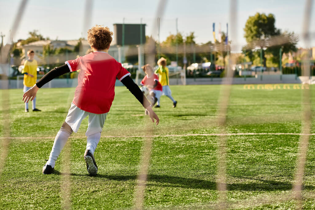 Grupa małych dzieci, wypełniona ekscytacją i energią, angażuje się w przyjazną grę w piłkę nożną. Biegają, kopią i gonią piłkę z entuzjazmem na zielonym polu pod jasnym słońcem.. - Zdjęcie, obraz