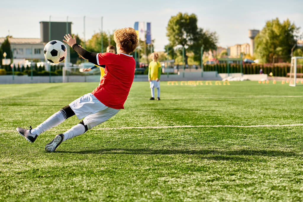 Młody chłopak energicznie kopie piłkę, wysyłając ją przez rozległe pole. Jego skoncentrowana ekspresja i precyzyjna technika pokazują jego pasję do sportu.. - Zdjęcie, obraz
