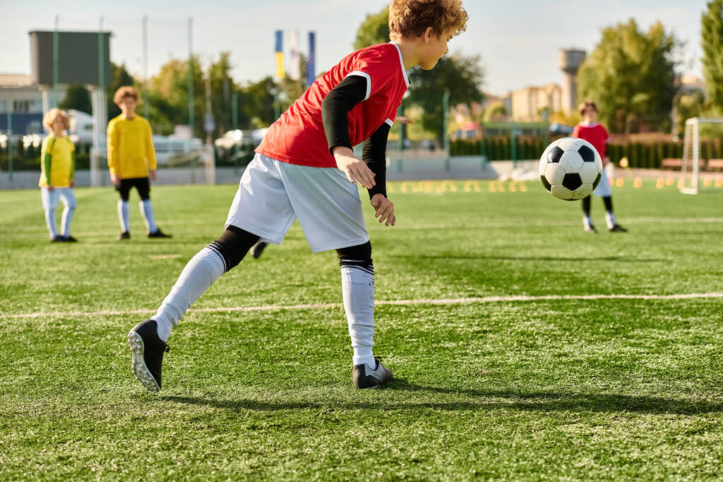 Een jonge jongen schoppen een voetbal op een grasveld, waaruit blijkt vastberadenheid en vaardigheid in zijn spel. - Foto, afbeelding