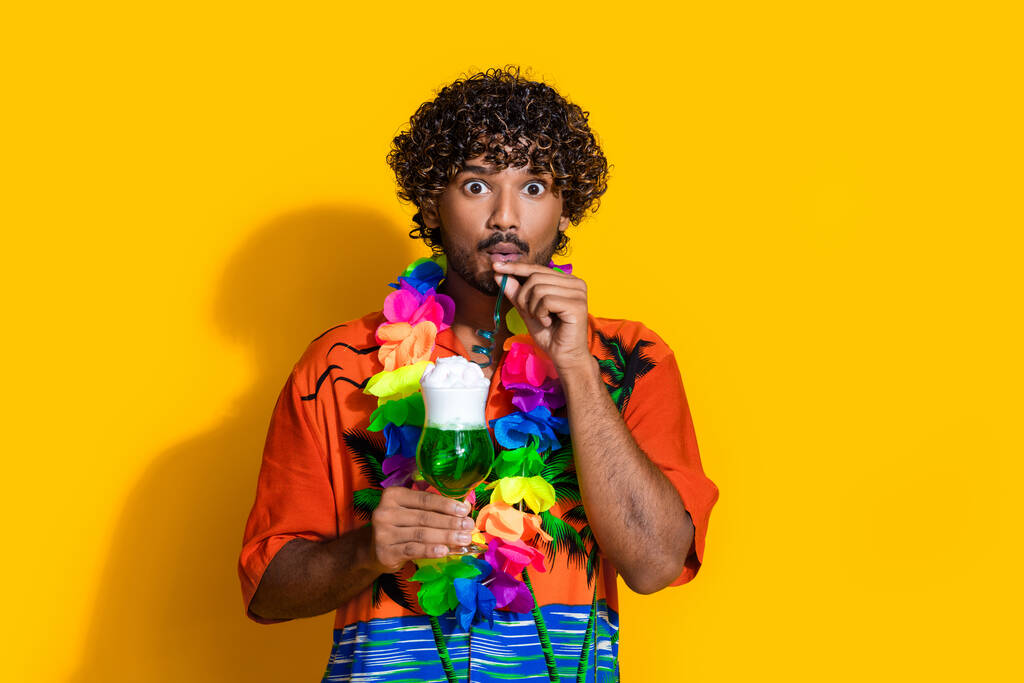 Retrato de hombre sin palabras usar camisa de impresión hawaii beber cóctel verde asombrado mirando aislado sobre fondo de color amarillo vibrante. - Foto, Imagen
