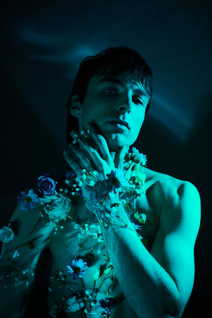 Чоловік без сорочки тримає в руках масив яскравих квітів - Фото, зображення