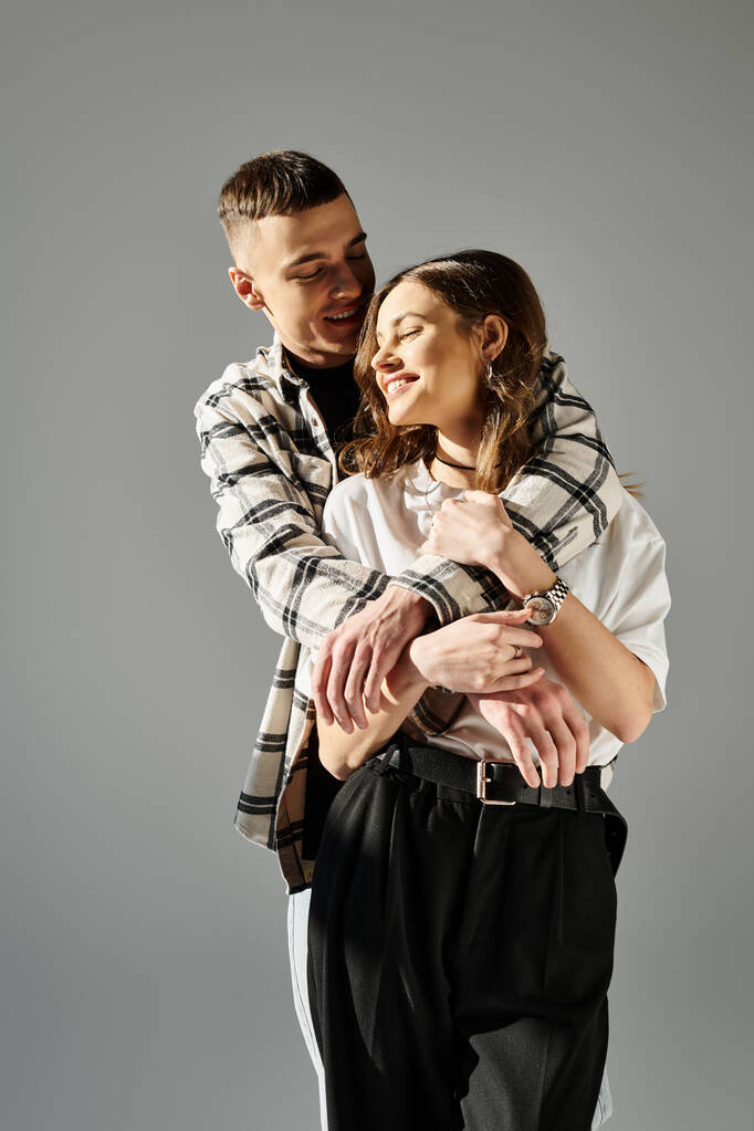 A man tenderly holds a woman in his arms, showing love and affection in a studio setting against a grey background. - Photo, Image