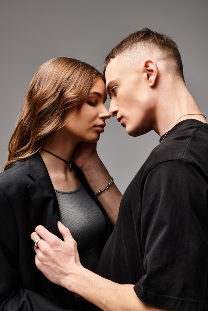 Um jovem e uma mulher de pé juntos, mostrando amor e conexão, contra um fundo de estúdio cinza. - Foto, Imagem