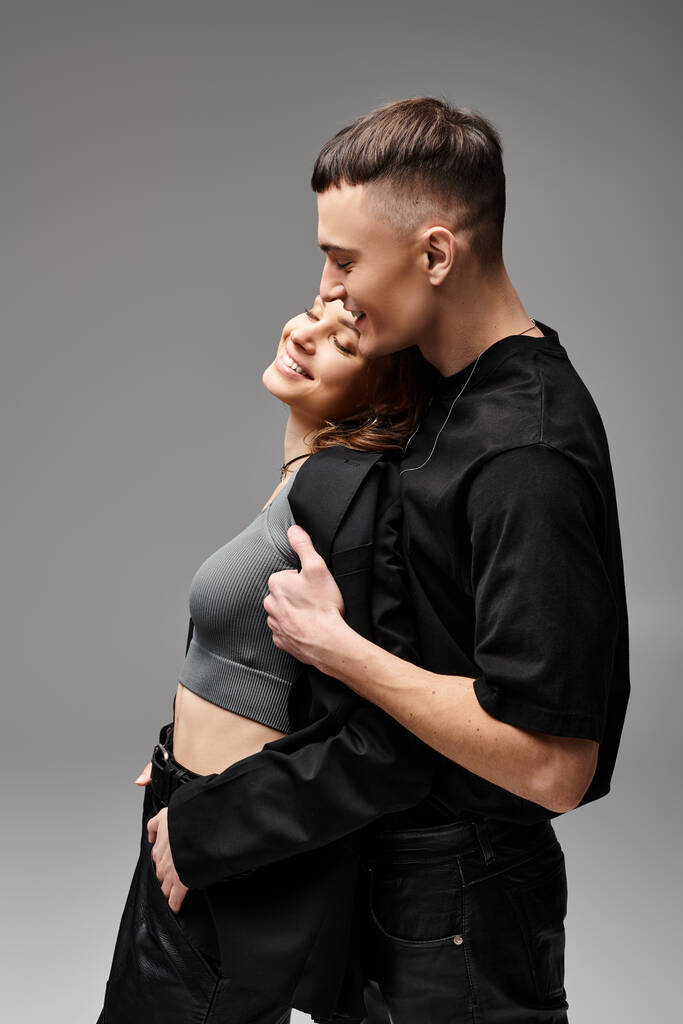 Ein junger verliebter Mann und eine junge Frau, die sich vor grauem Hintergrund in einem Studio leidenschaftlich umarmen. - Foto, Bild