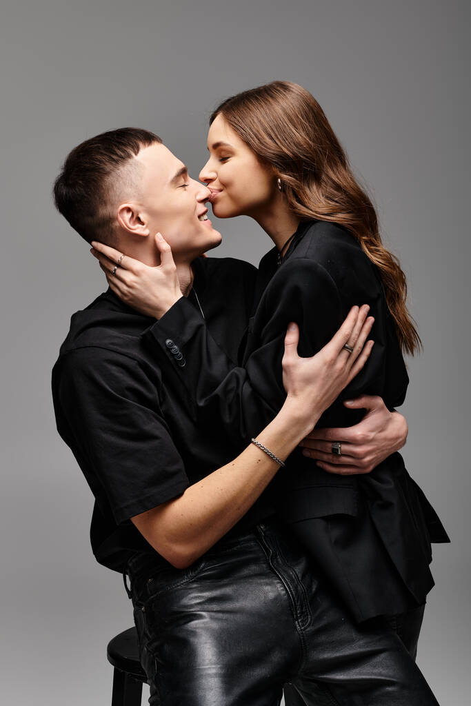 Um jovem casal apaixonado apaixonadamente se beijando em um estúdio com um fundo cinza. - Foto, Imagem