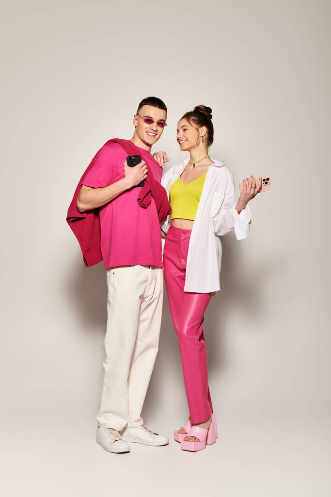 A stylish young couple stands close together, exuding love and connection in a studio against a grey background. - Photo, Image