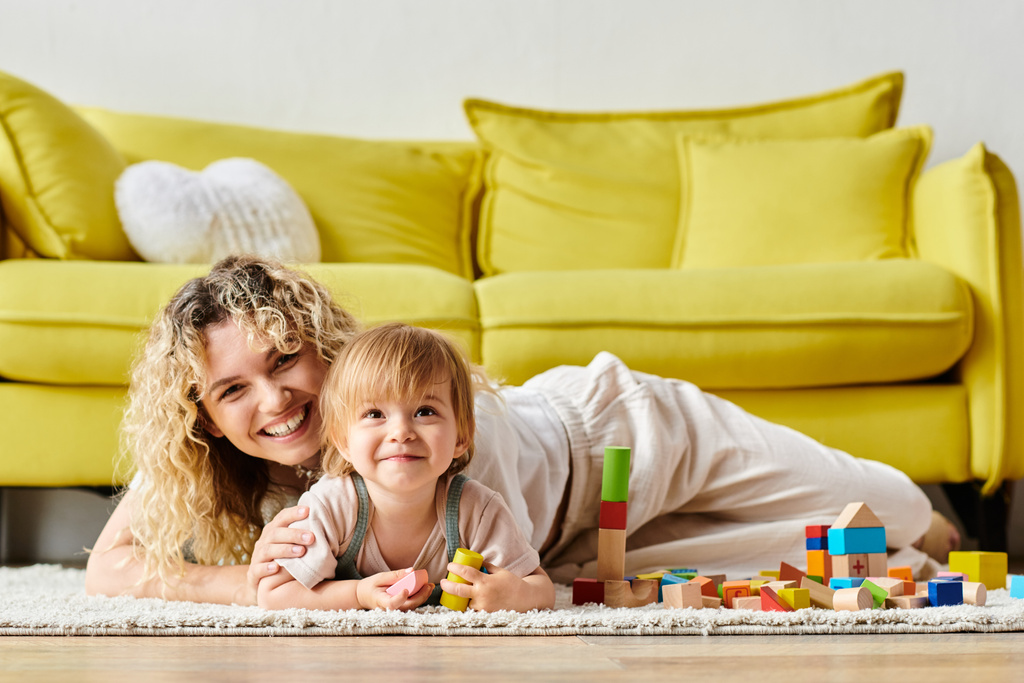 Egy göndör anya és a kislánya Montessori tanulásba kezdenek, kényelmesen szétterülve otthon a padlón.. - Fotó, kép