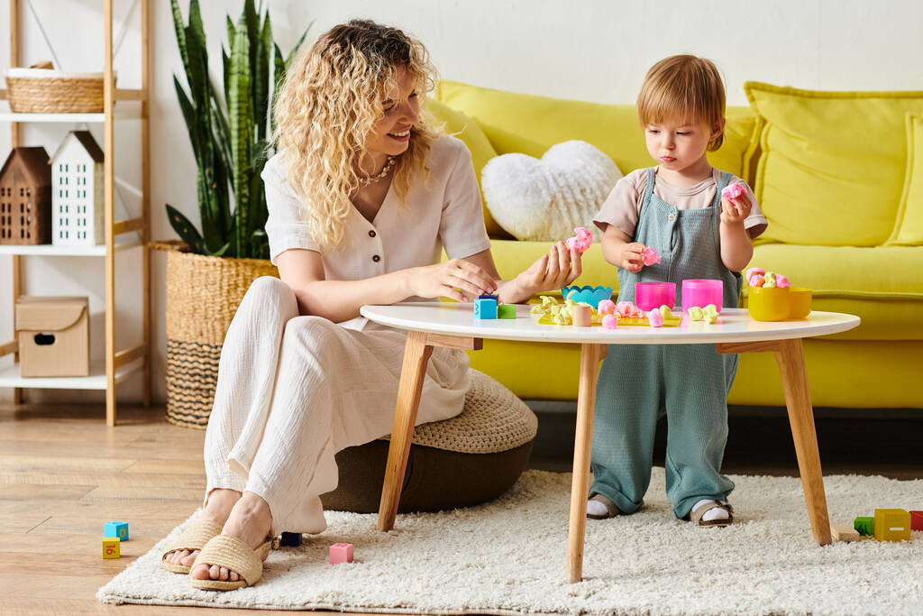 Een krullende moeder en haar peuterdochter doen Montessori-activiteiten in een gezellige woonkamer. - Foto, afbeelding