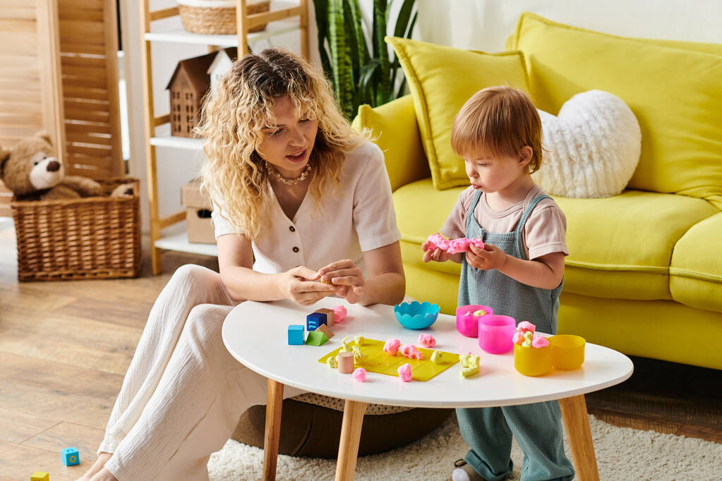 Lockige Mutter und Kleinkind-Tochter spielen fröhlich mit Spielzeug und praktizieren zu Hause Montessori-Erziehung. - Foto, Bild