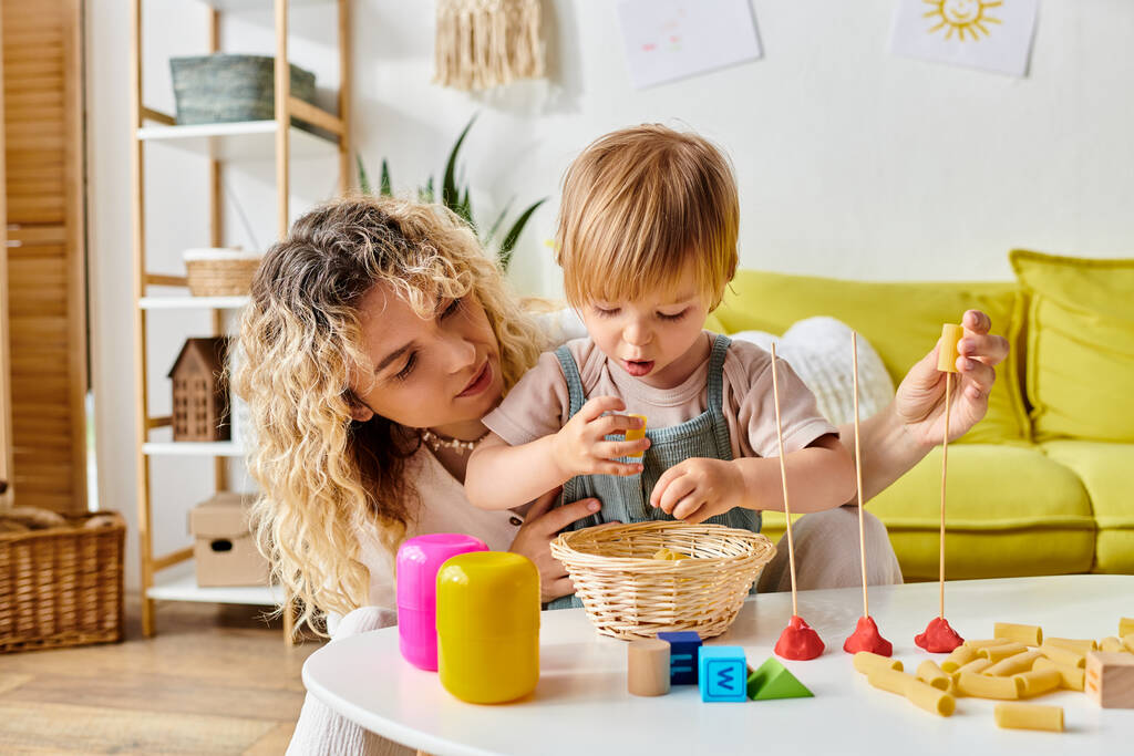 Kędzierzawa matka i jej córeczka szczęśliwie bawią się zabawkami, ucząc się Montessori w domu. - Zdjęcie, obraz