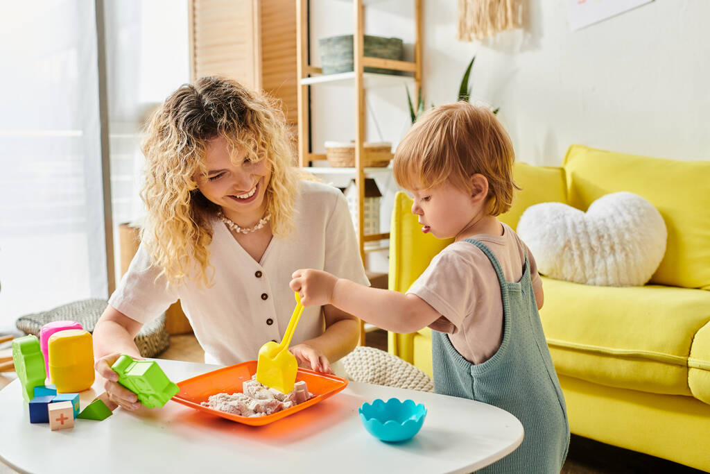 Een moeder met krullend haar en haar peuterdochter spelen vrolijk met educatief Montessori speelgoed thuis. - Foto, afbeelding