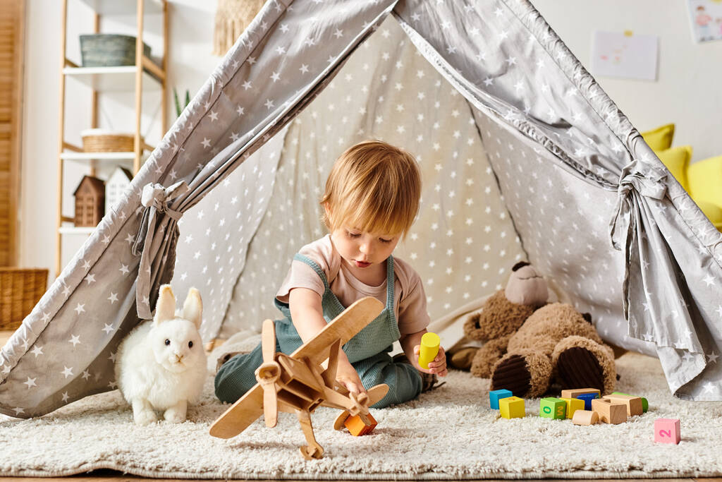 lapsi tyttö pelaa onnellisesti leluja sisällä leikkisä teltta kotona. - Valokuva, kuva