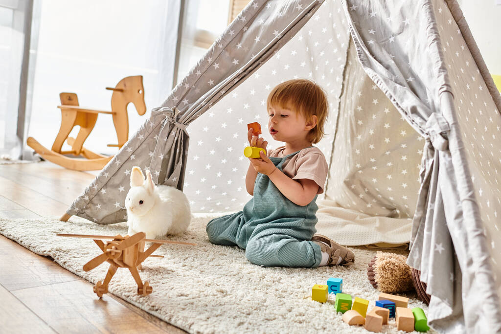 Ein kleines Kind, das in einem lebhaften Spielzelt nach Montessori-Methode mit Spielzeug spielt. - Foto, Bild