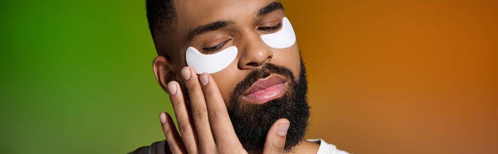 Un bel giovane uomo con macchie bianche sul viso, concentrandosi sulla sua routine di cura della pelle. - Foto, immagini