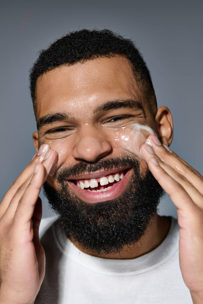 Un homme barbu appliquant joyeusement de la crème sur son visage. - Photo, image