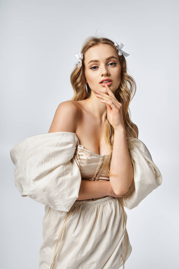 Une jeune femme blonde mettant en valeur la grâce et le style dans une robe blanche tout en posant pour une photo dans un cadre studio. - Photo, image