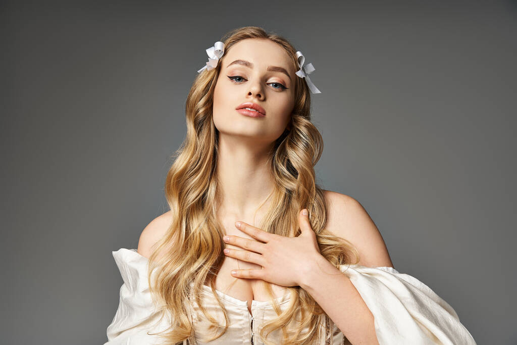 Uma jovem mulher com cabelo loiro longo, vestida com um vestido branco fluindo, exala um senso de beleza etérea em um estúdio. - Foto, Imagem