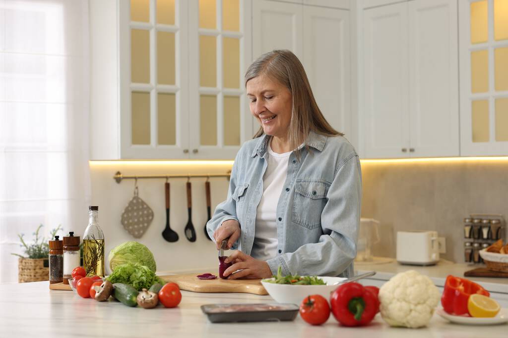 Onnellinen nainen leikkaa sipulia pöydässä keittiössä - Valokuva, kuva