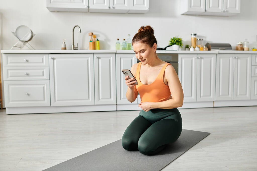 Middelbare vrouw op yoga mat controleren smartphone. - Foto, afbeelding