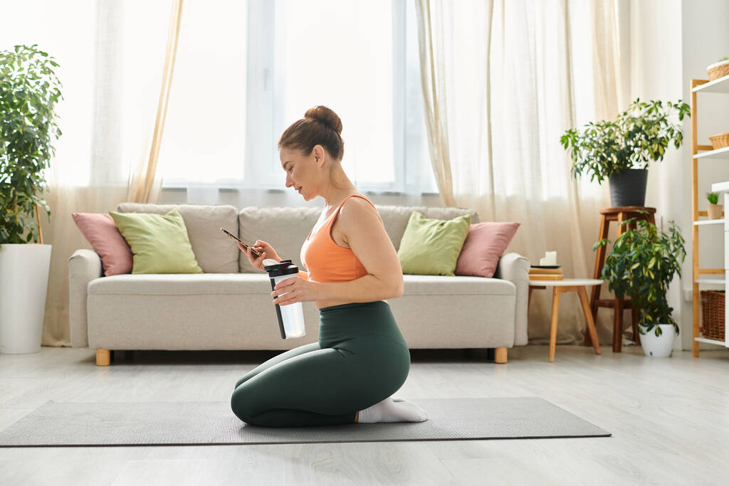 Mujer de mediana edad meditando serenamente sobre una esterilla de yoga en una acogedora sala de estar. - Foto, imagen