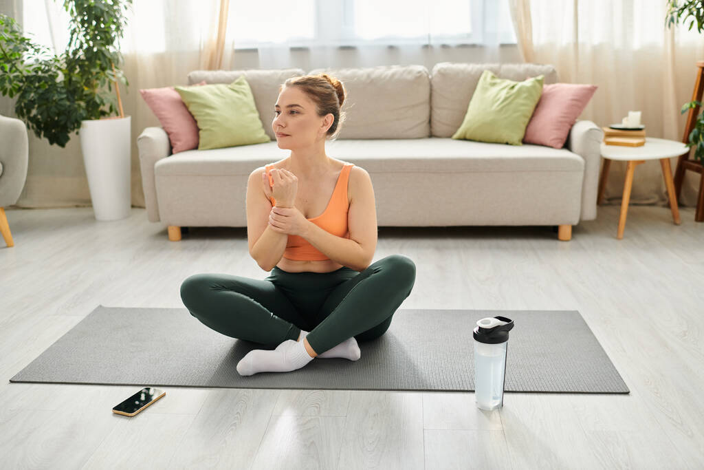 Mujer de mediana edad practicando yoga en una estera en su sala de estar. - Foto, imagen