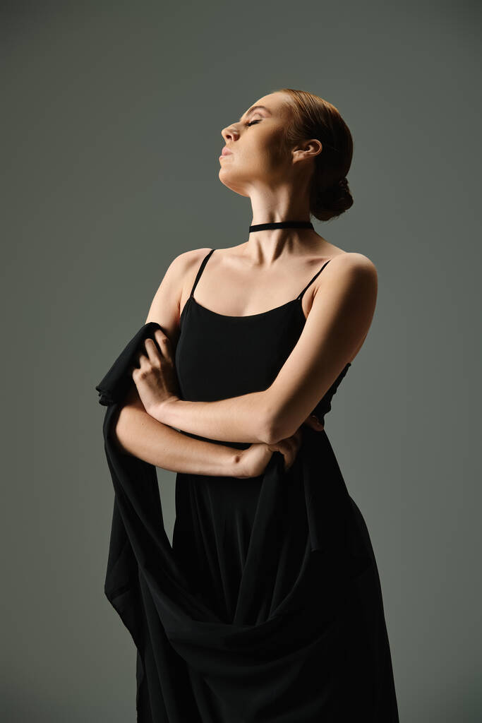 Eine junge schöne Ballerina in einem schwarzen Kleid mit verschränkten Armen. - Foto, Bild