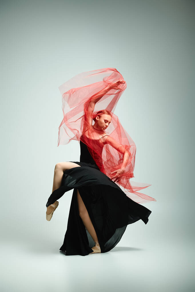 Siyah elbiseli ve kırmızı eşarplı genç bir kadın zarif bir şekilde dans ediyor.. - Fotoğraf, Görsel